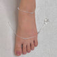 Silver anklet on a foot against a neutral background